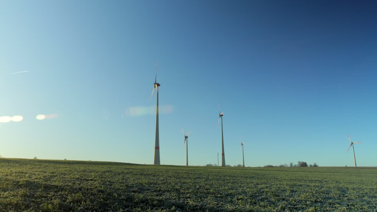 Time-lapse of an cold morning as the sun rises on a small wind farm with a small agricultural farm in the foreground with planes going by