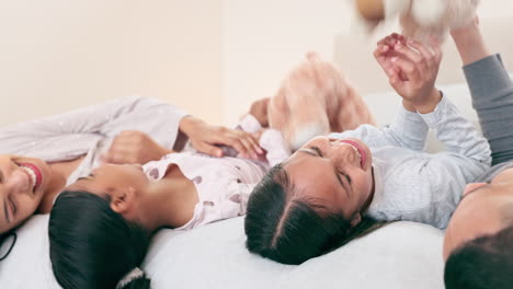 padres, cama y peluche jugando con los niños