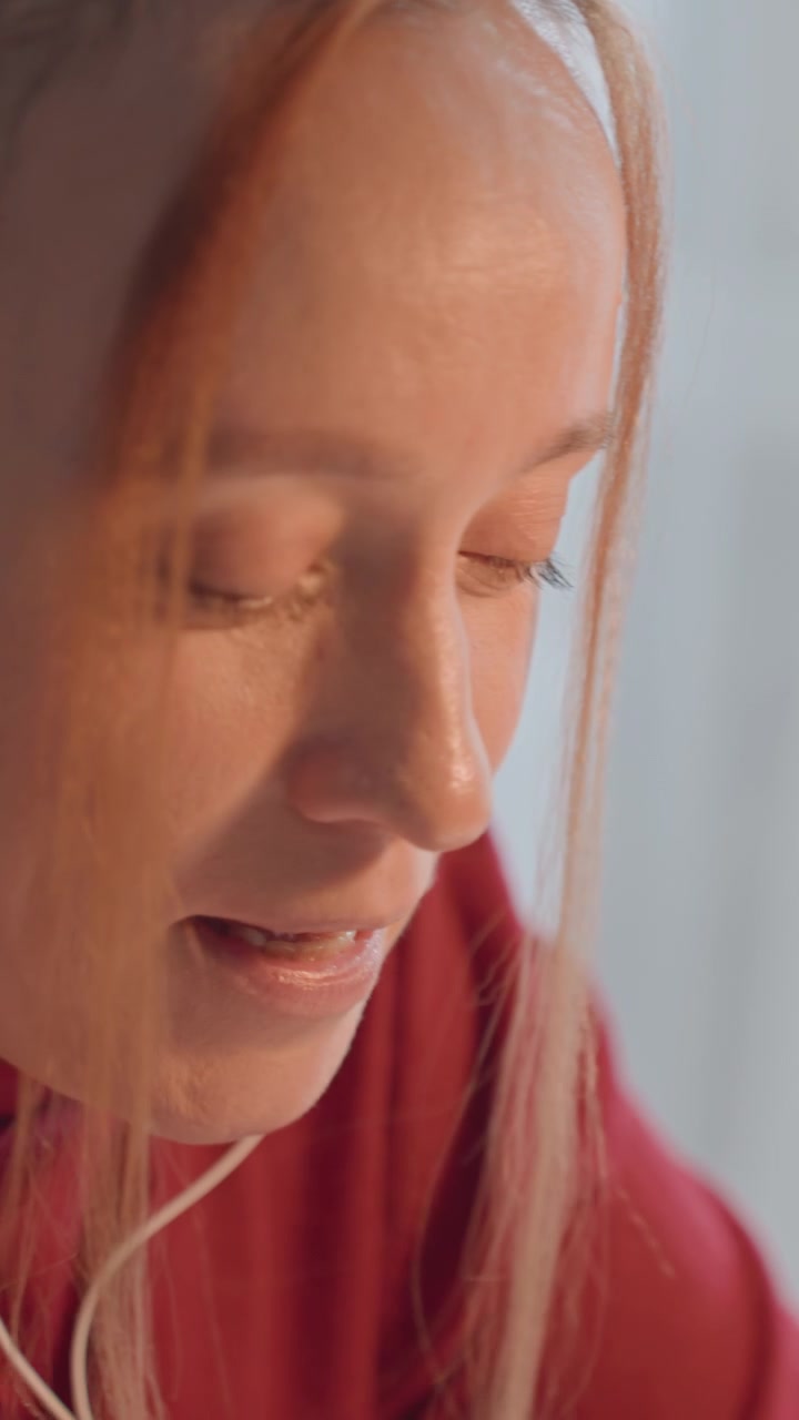 Close up of young woman with long light brown hair wearing. Her eyes are closed in some frames while woman appears. Focus remains steady on her profile throughout sequence