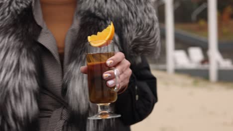 woman holding a cup of tea with orange slice