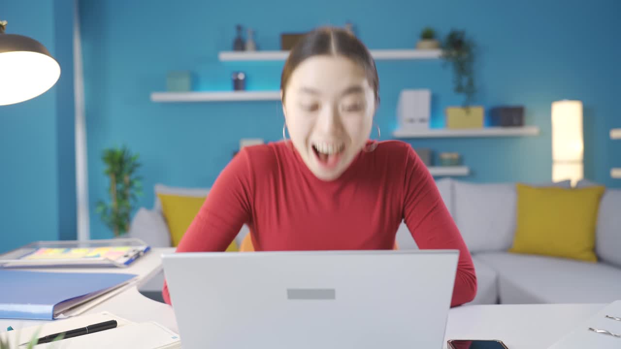 책상에서 노트북을 보는 여자는 노트북에서 보는 것을 보고 기 ⁇ 으로 비명을 지른다.