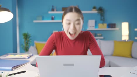 책상에서 노트북을 보는 여자는 노트북에서 보는 것을 보고 기 ⁇ 으로 비명을 지른다.
