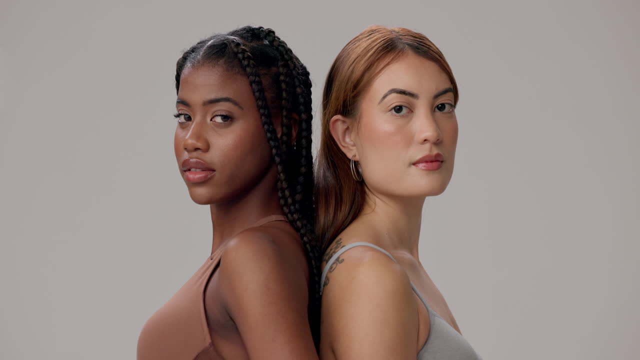 Two young women standing back to back, looking at the camera.