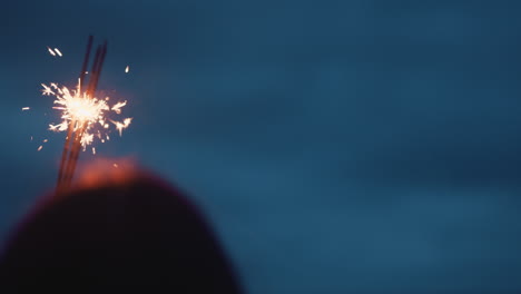 Mujer-Sosteniendo-Bengala-Celebrando-La-Víspera-De-Año-Nuevo-En-La-Playa-Por-La-Noche-Viendo-Hermosas-Chispas