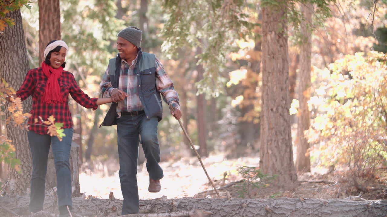 Senior couple in a forest walk to camera, on left of frame