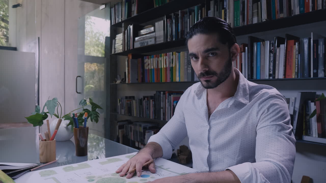 hombre trabajando en planos y mirando a la cámara ms de arquitecto latinoamericano trabajando en