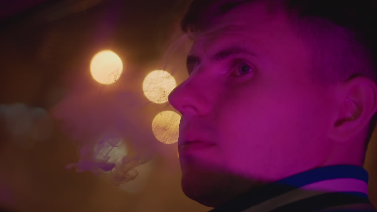 Young male driver at night, neonlit car interior with purple glow and warm bokeh closeup profile exhaling vapor, reflective expression, streetlights through window, cinematic moody atmosphere