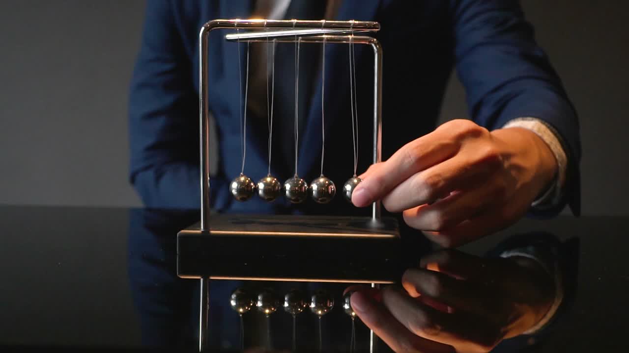 fotografía cortada de un hombre de negocios tirando de la pelota de newton cradle