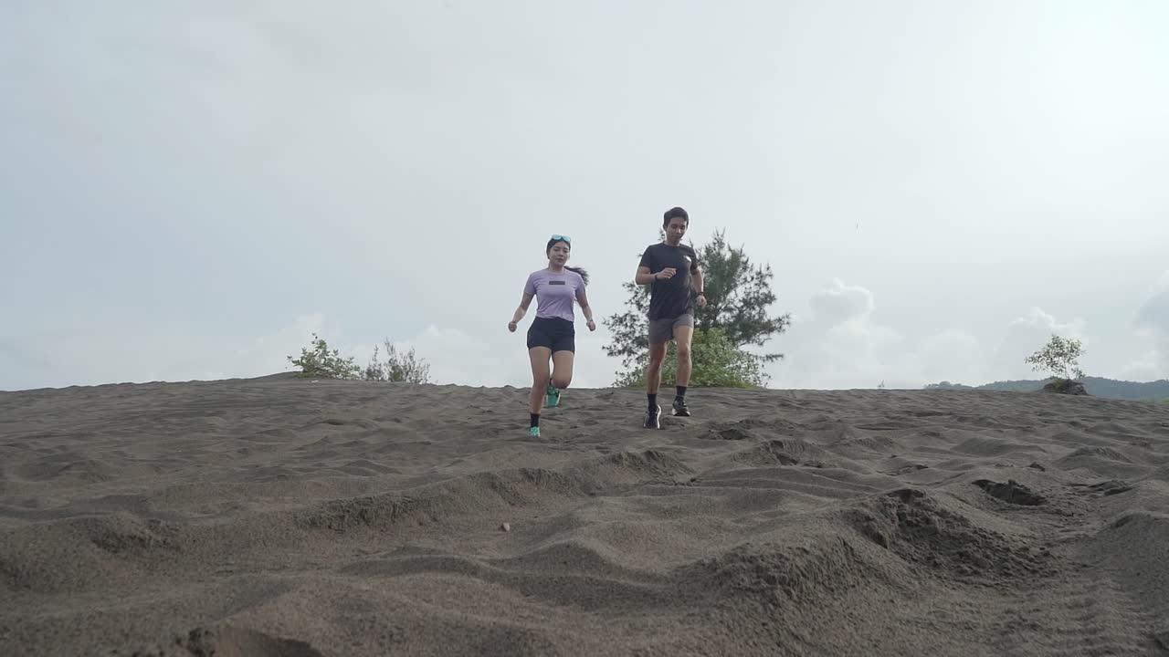 Couple Running Up a Sand Dune