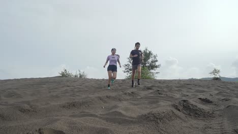 couple running up a sand dune