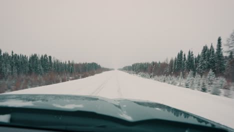 Truck-POV-Driving-Fast-Down-a-Snow-Covered-Winter-Highway-with-Trees-on-Both-Sides