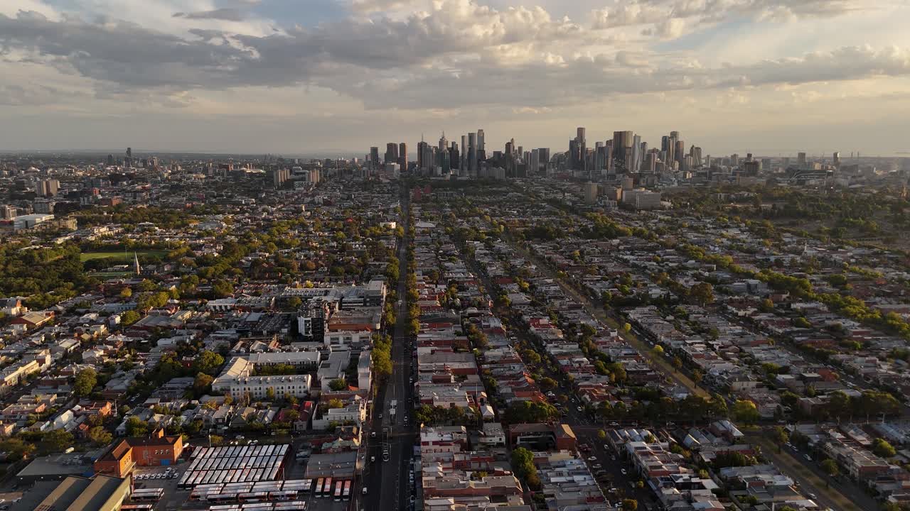 Aerial view of a vast cityscape with a prominent road leading to a distant skyline under a cloudy sky.