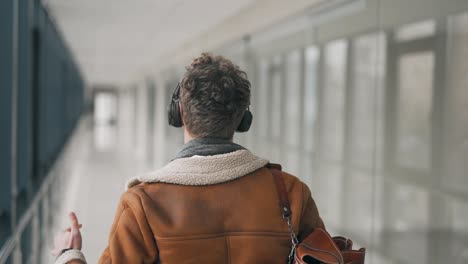 rear view of a man walking down the hall in headphones and dancing