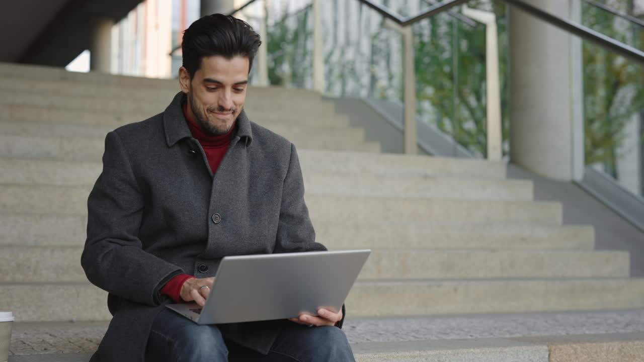 Man celebrating success while working on laptop outdoors