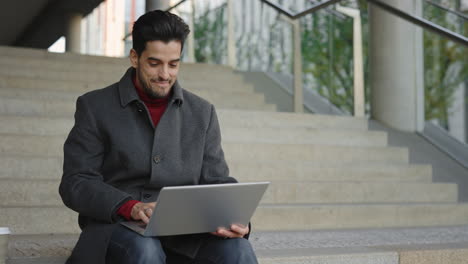 man celebrating success while working on laptop outdoors