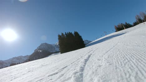 a skier going down a slope, in the background a blue sky with bright sun and ski lift view from the skier’s back