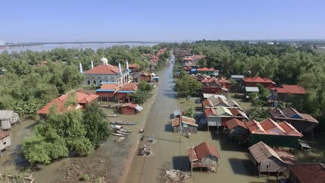 aerial : flying over motorbikes and people walking on flooded street through a muslim village