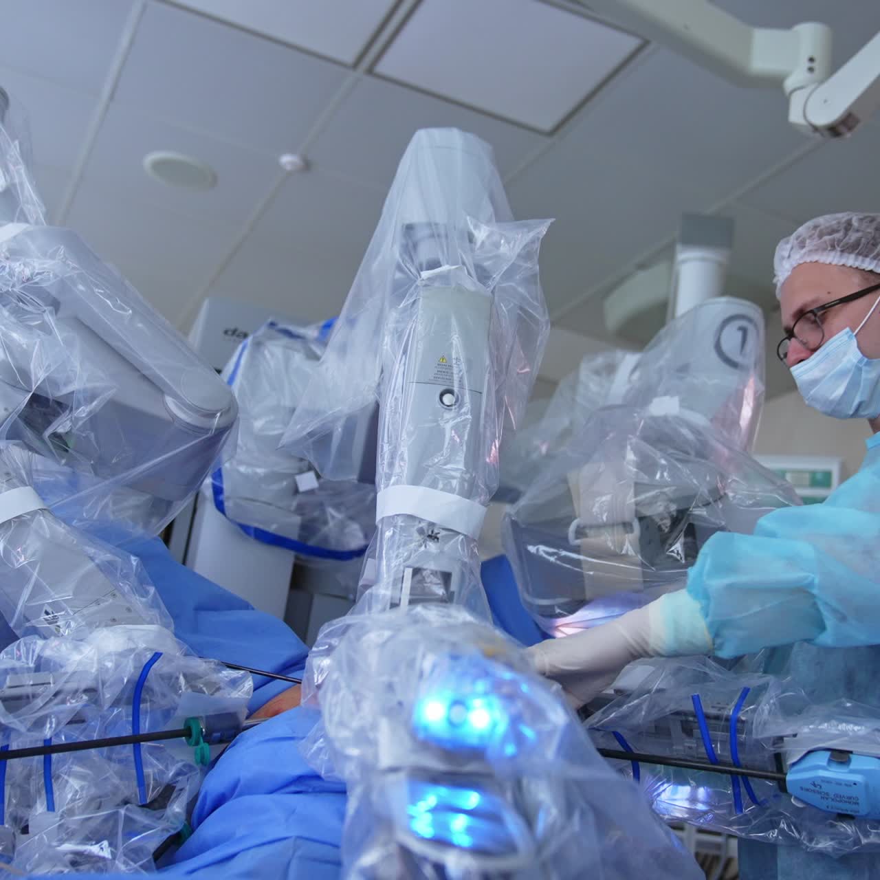 Young male doctor performs operation in collaboration with robotic equipment. High-precise technique helping the patients and doctors at surgery. Los angle view