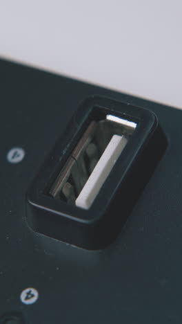 young man plugs usb cable into modern black connecting hub port on white background extreme close view