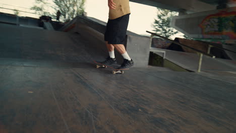 teenager practicing stunt jump on skate board at urban skate park.