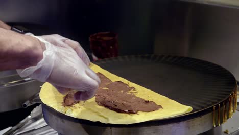 gloved hands making crepes