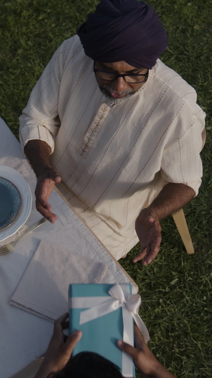 Presenting a Gift to an Elderly Man in a Turban Outdoors
