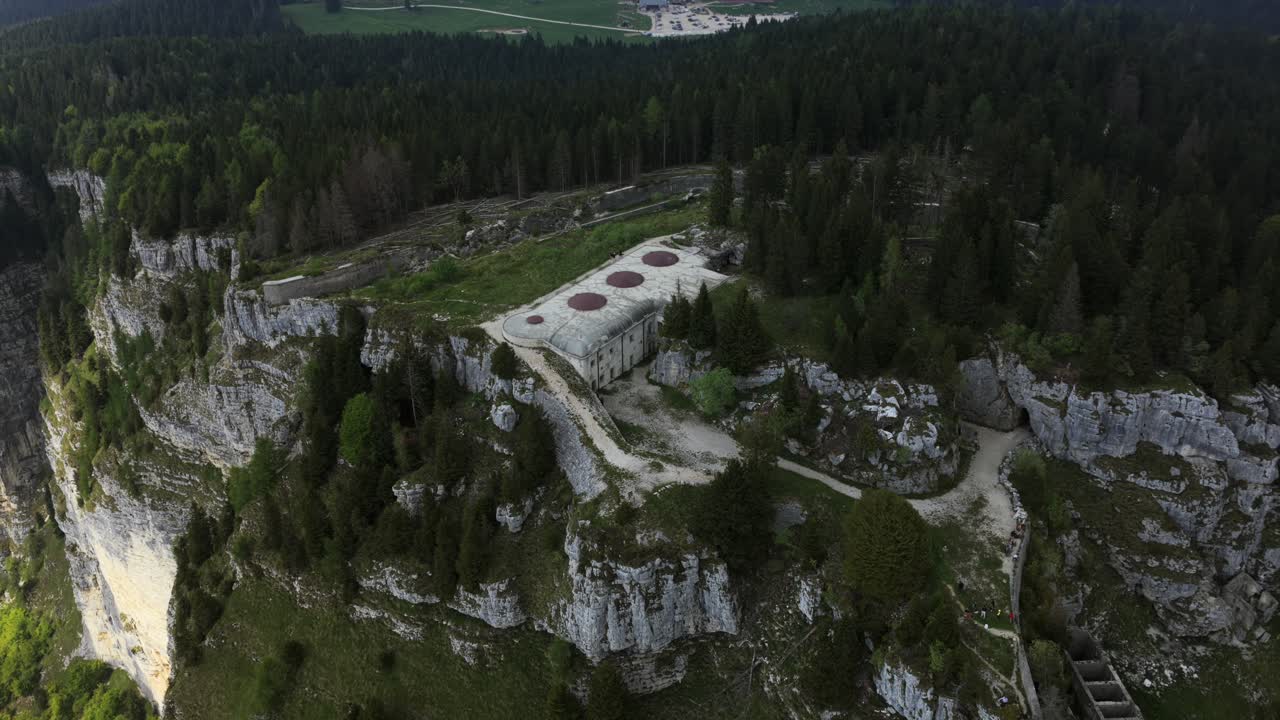 Forte Campolongo—drone ascends and dolly-outs from a tight overhead of the WWI fort to a sweeping wide of limestone cliffs and forest