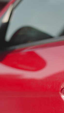 elegant woman with long red hair gets into modern automobile. female driver prepares to go on business on blurred background closeup backside view