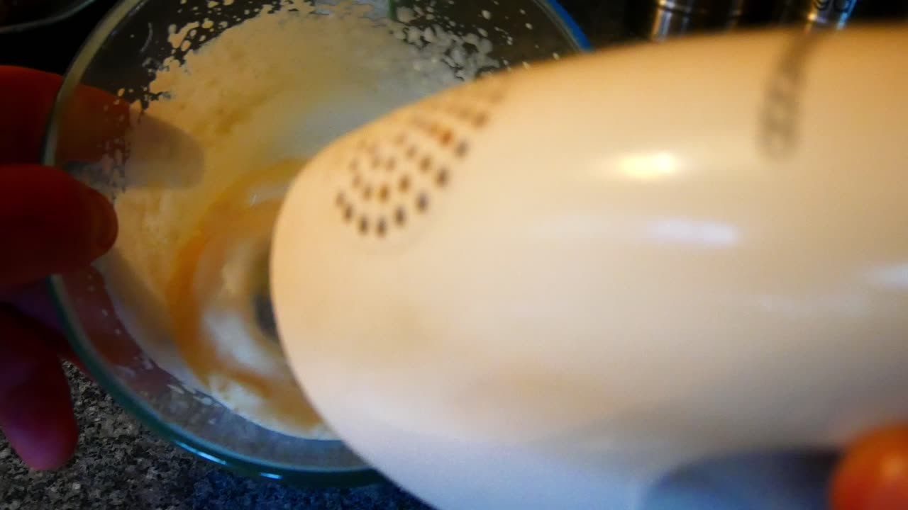 Making homemade whipped cream stiff peaks stirring with kitchen food mixer top down shot