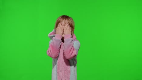little blonde child in unicorn costume crying, wiping tears with her hands on chroma key background