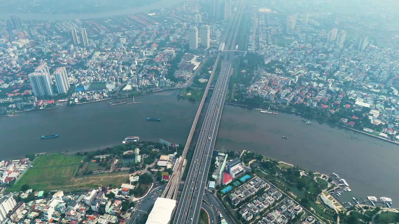 Aerial: Saigon Bridge during the day with fog, traffic, cityscape, and the Saigon River in Ho Chi Minh City, Vietnam, establishing drone shot