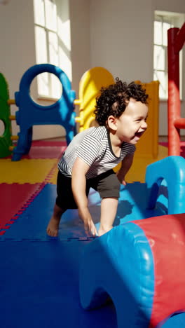 joyful toddler playing in a colorful indoor soft play area