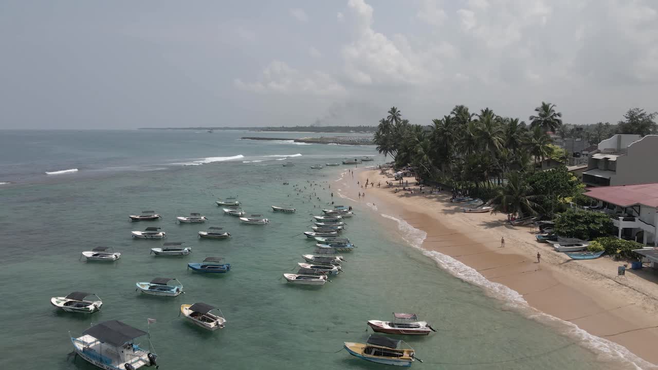 sobrevuelo bajo de barcos amarrados y nadadores en la playa arenosa de sri lanka