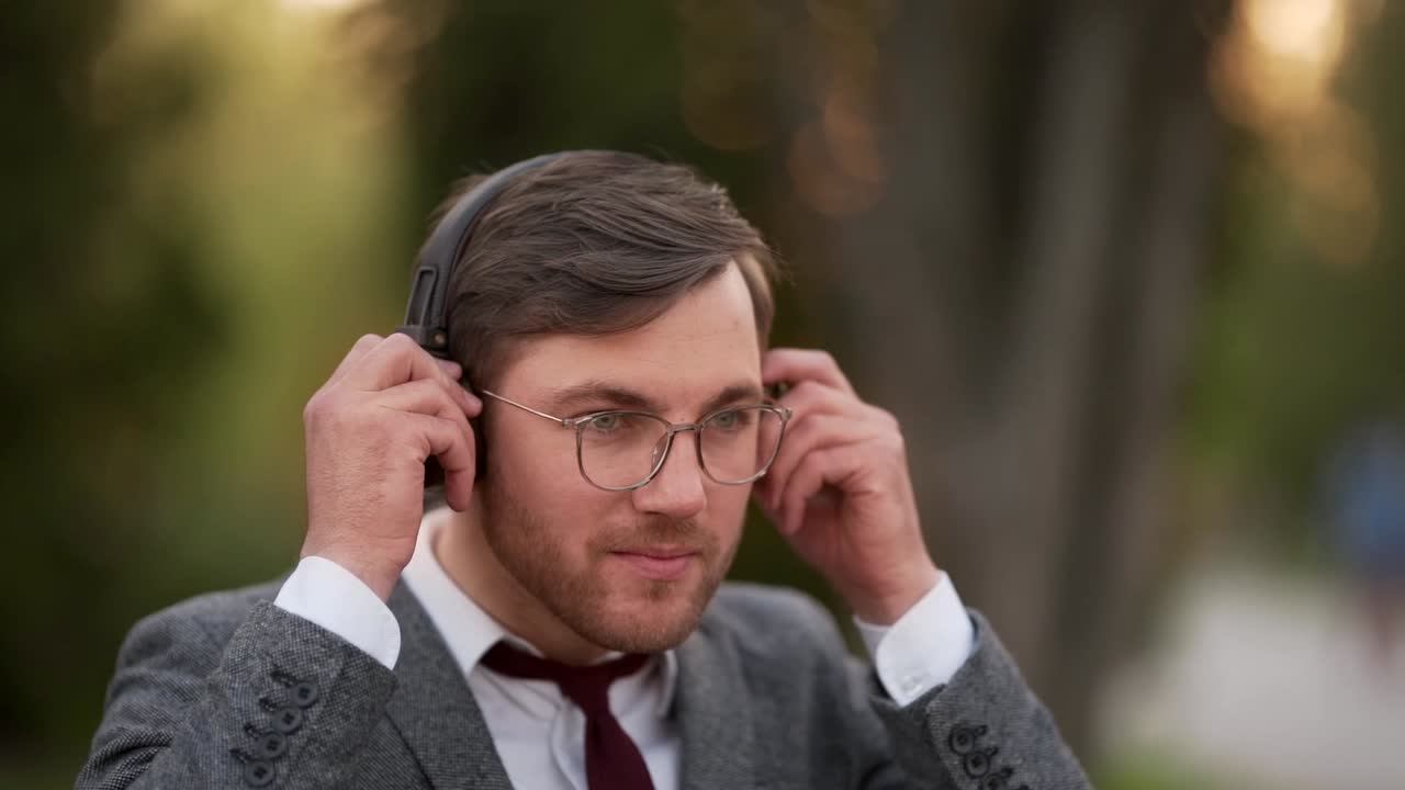 primer plano retrato joven hombre sólido usando auriculares elegantes y zumbando con música