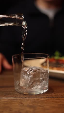 pouring water into a glass with ice