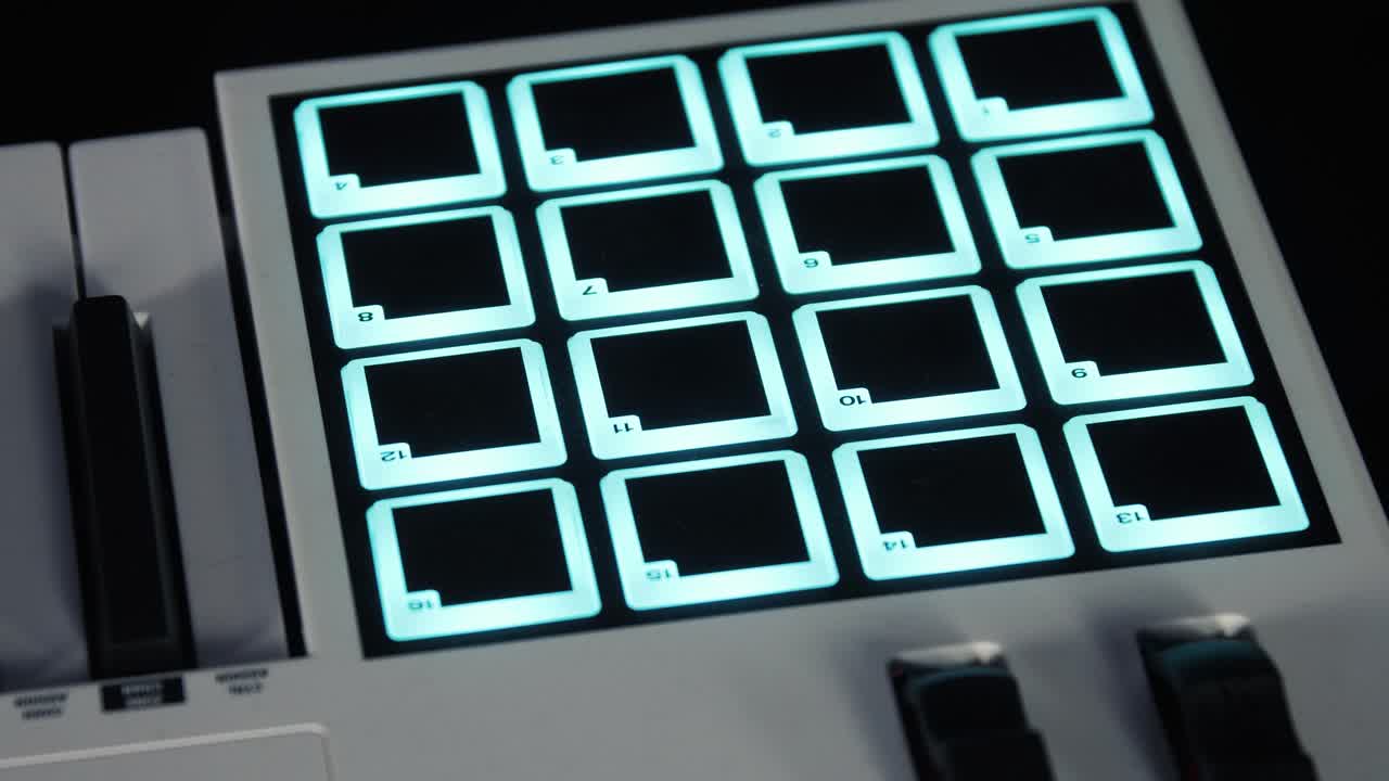 MIDI keyboard with an illuminated drum pad controller, glowing square pads in a dark setting