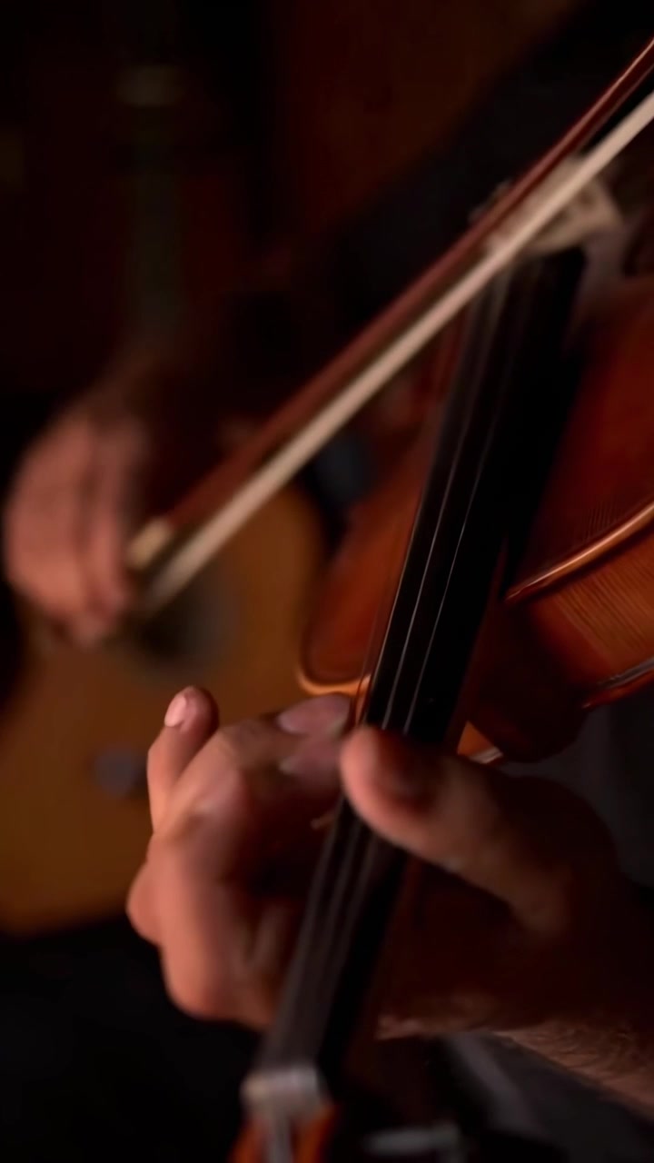 Musician Playing Violin with Acoustic Guitar in Background