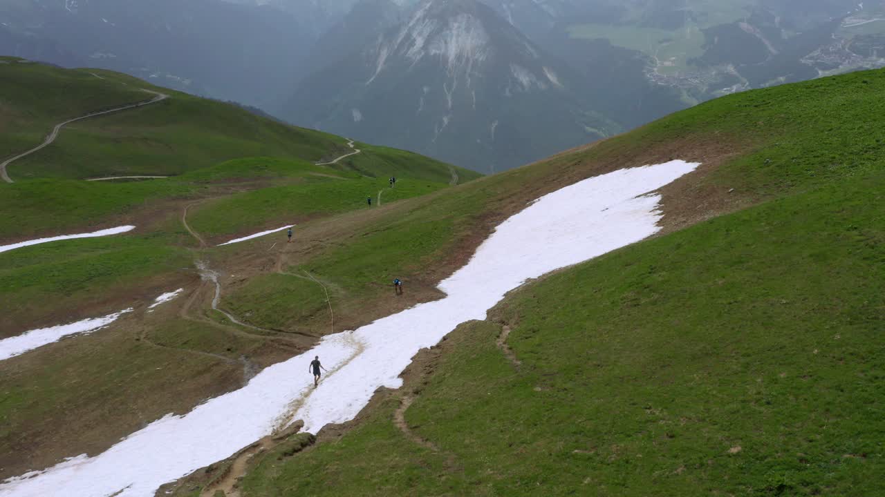 Aerial shot circling around a group of Fell runners in the French Alps on an overcast day
