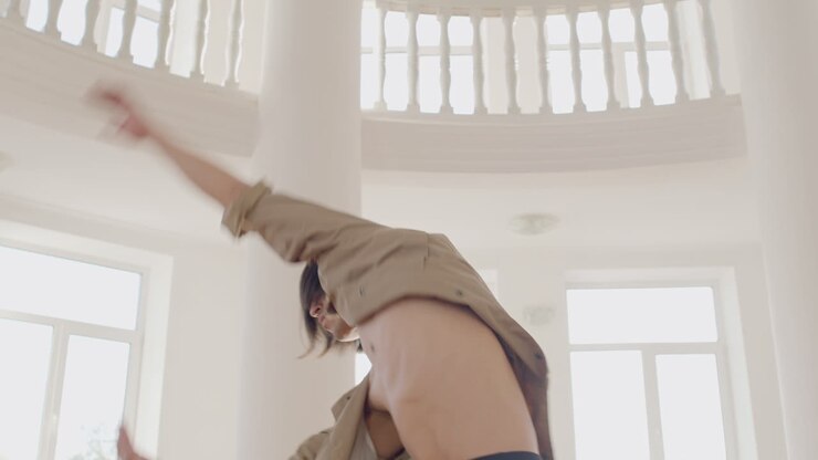 Vista dal basso di un danzatore giapponese contemporaneo uomo che si allena con passi di danza al centro dello studio
