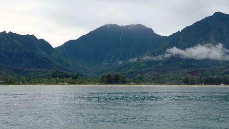 hd 120fps hawaii kauai boating on the ocean floating right to left with beach and clouds in the valley with mountain with waterfall in cloudy distance, slight right to left pan
