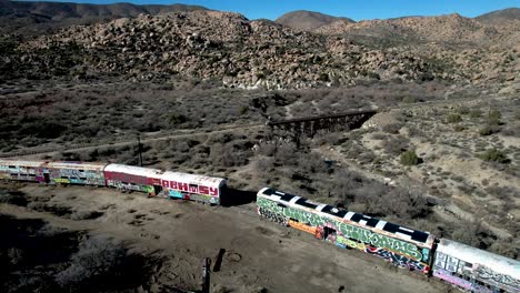 high panning aerial view of california desert with abandoned train cars