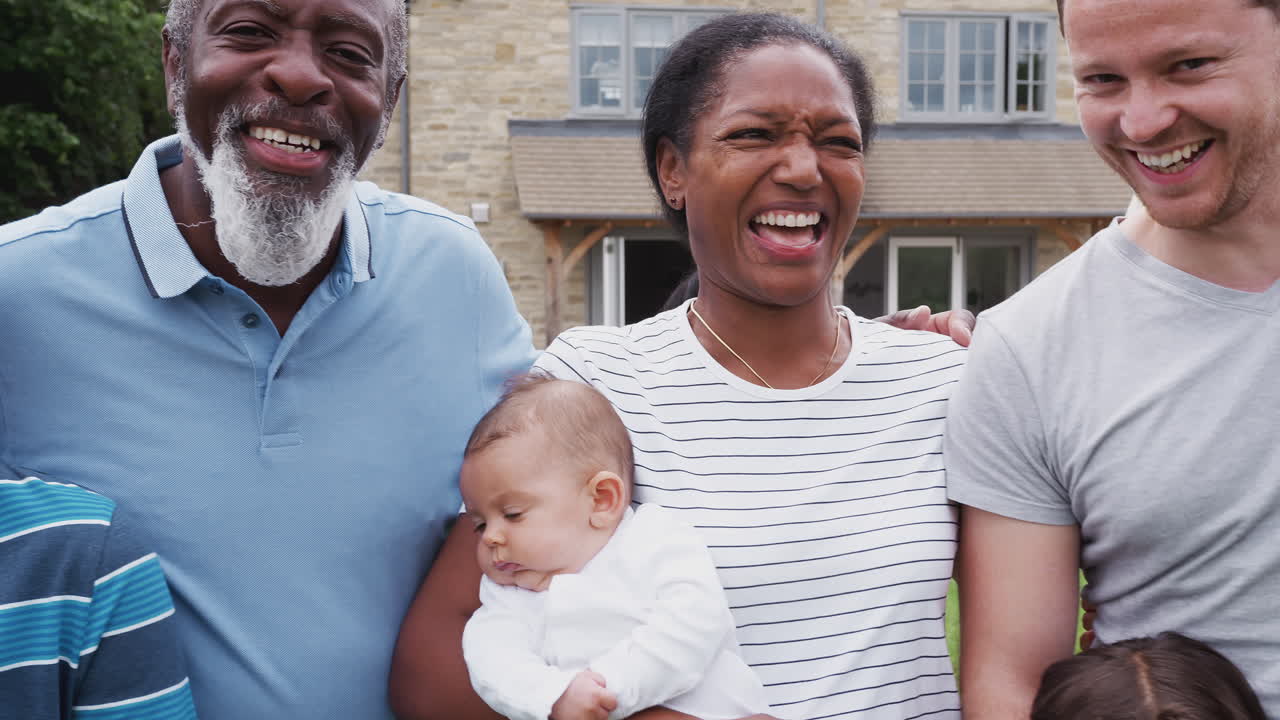 retrato de una familia de raza mixta de varias generaciones sonriente en el jardín de su casa