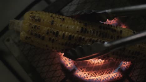 Colocando-Maíz-En-La-Mazorca-Cocinando-En-Una-Estufa-De-Gas-Sobre-Una-Parrilla-Desde-Arriba-A-Cámara-Lenta