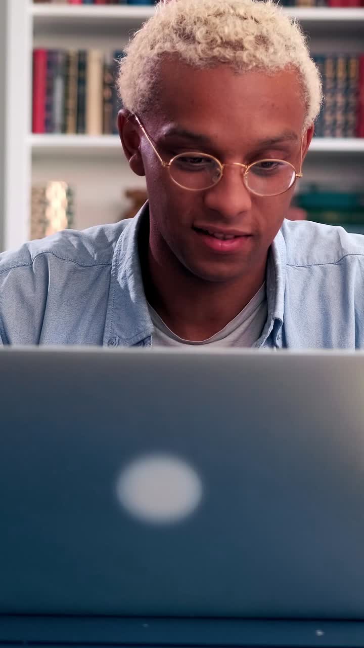 A young man focused on working on his laptop sitting in a cozy room and