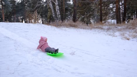 toddler girl trying sledding like snowboarding