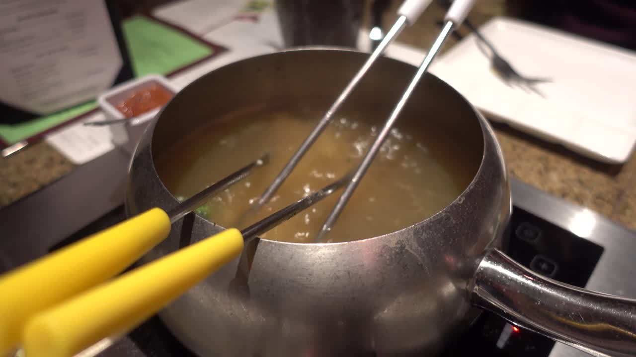Fondue pot boiling with hot oil and food cooking inside