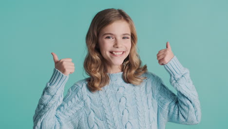 teenage caucasian girl with thumbs up looking at the camera.