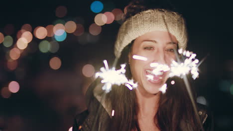 Feliz-Mujer-Caucásica-Sosteniendo-Bengalas-Bailando-En-La-Azotea-Por-La-Noche-Celebrando-La-Víspera-De-Año-Nuevo-Disfrutando-De-La-Celebración-Navideña