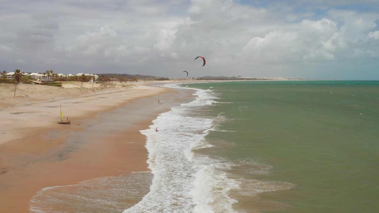 antena: cumbuco durante el día con gente haciendo kitesurf