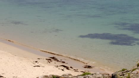 looking down onto the beach with the sea lapping on to the sand on st agnes and gugh at the isles of scilly